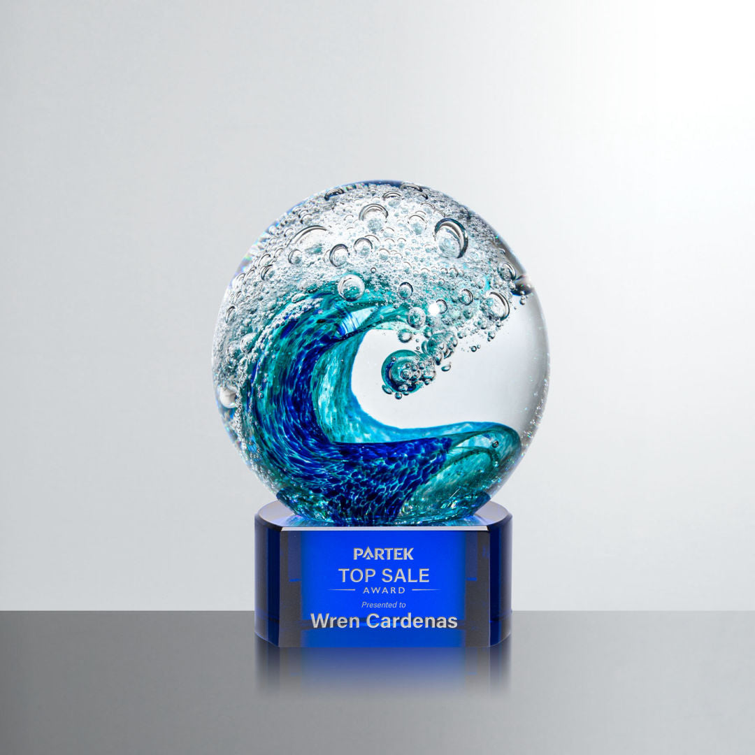 Art glass sphere on blue glass base with wave design